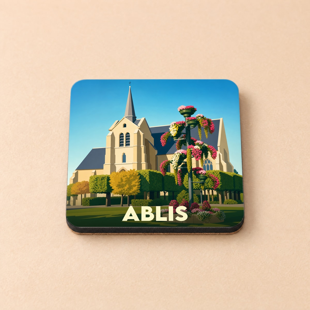 Dessous de verre souvenir de la ville de Ablis avec une illustration stylisée de son église et de parterres fleuris.
