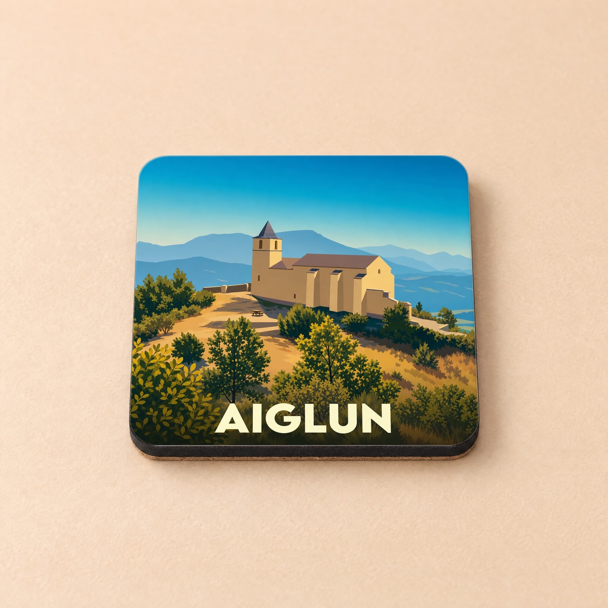 Dessous de verre souvenir de la ville d'Aiglun avec une illustration stylisée d'une église perchée en montagne.