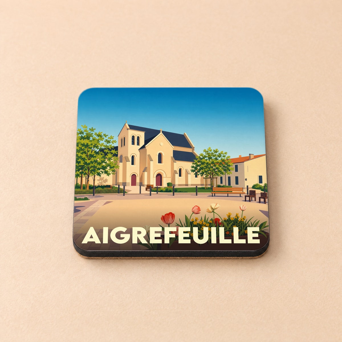 Dessous de verre souvenir de la ville d'Aigrefeuille illustrant son église et sa place principale dans un style graphique épuré.