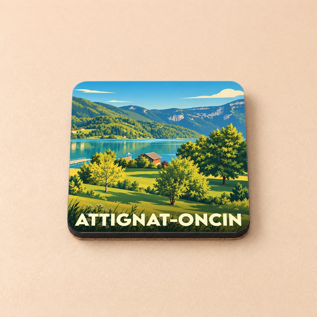 Dessous de verre souvenir d'Attignat-Oncin avec une illustration stylisée d'un paysage de lac et de montagnes.
