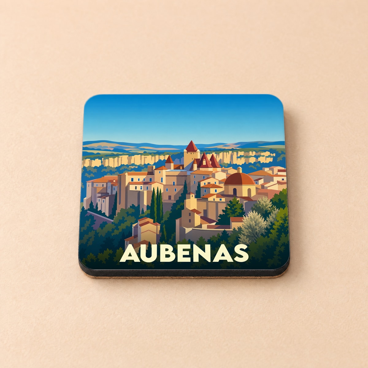 Dessous de verre souvenir de la ville d'Aubenas avec une illustration stylisée d'un paysage urbain provençal.