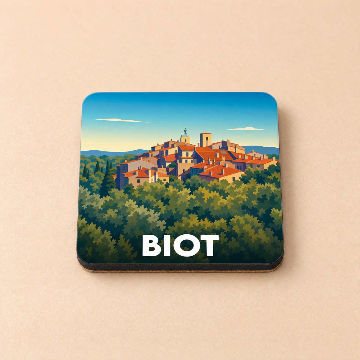 Dessous de verre souvenir de la ville de Biot avec une illustration stylisée d'un village perché.