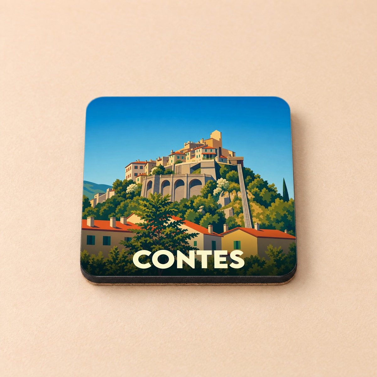 Dessous de verre souvenir de la ville de Contes avec une illustration stylisée d'un village perché.