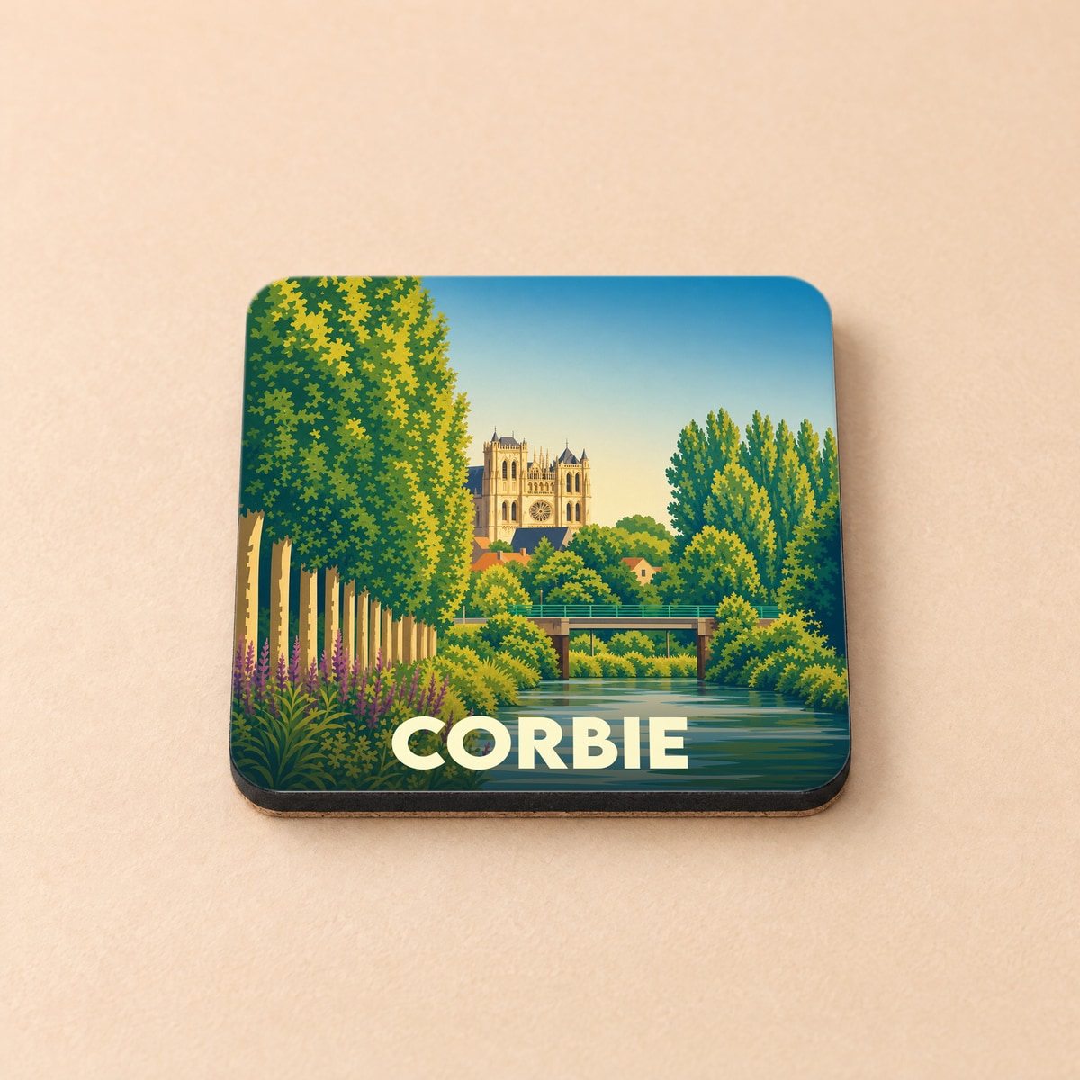 Dessous de verre souvenir de la ville de Corbie avec une illustration stylisée de son abbaye et de la Somme.
