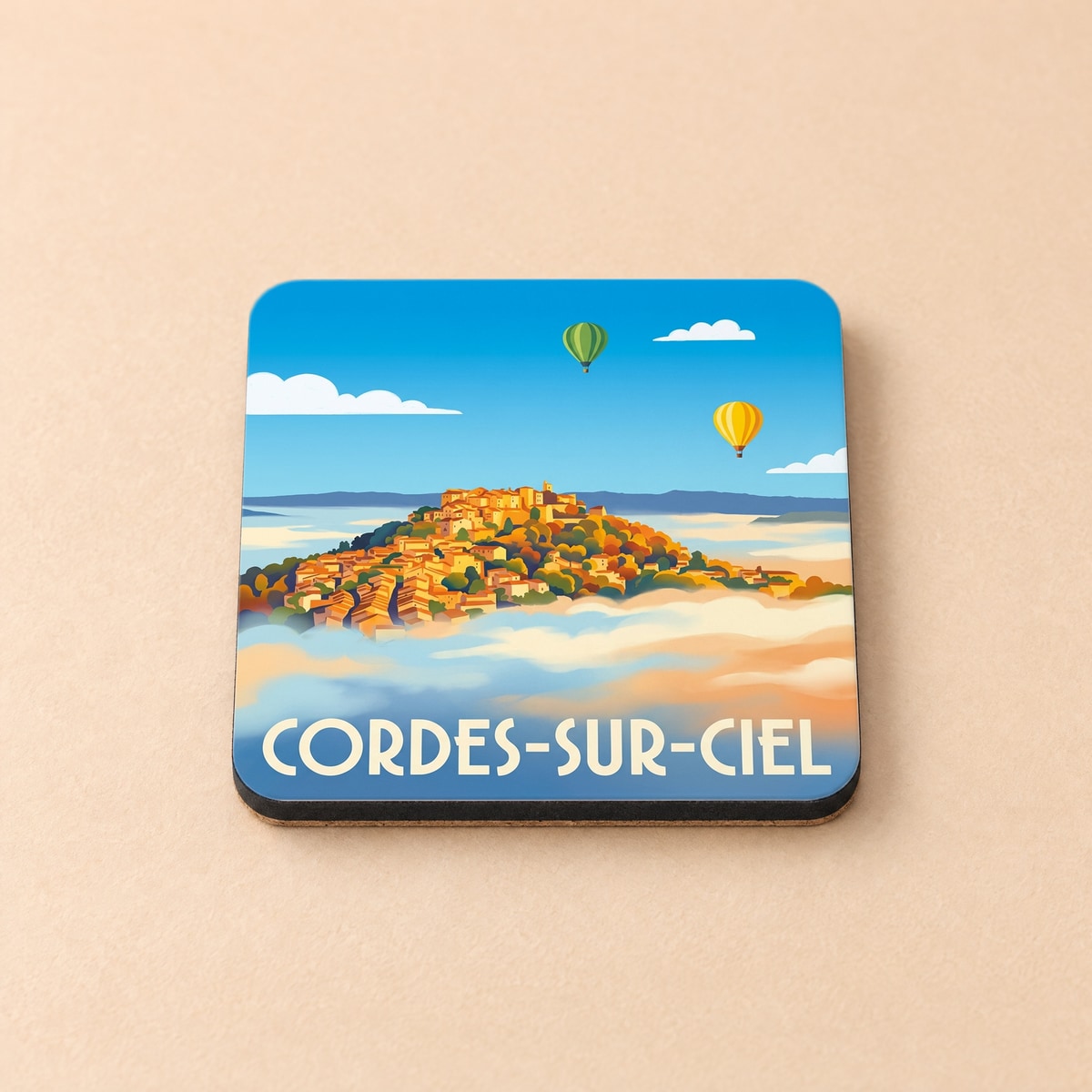 Dessous de verre souvenir de Cordes-sur-Ciel avec une illustration stylisée d'un village perché au-dessus des nuages.