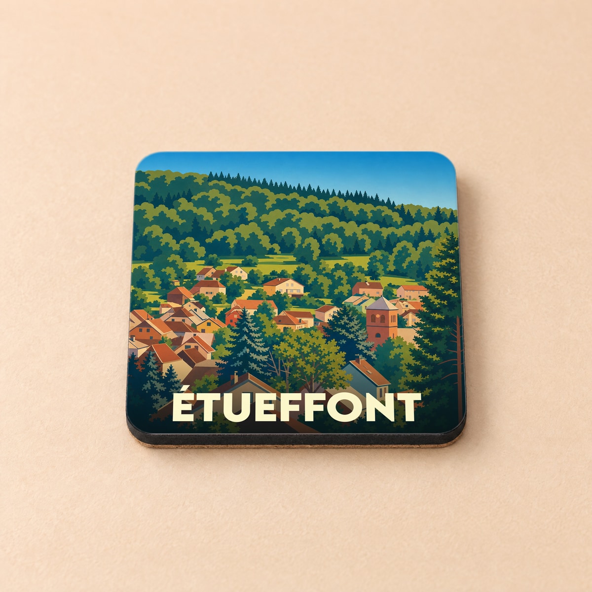 Dessous de verre souvenir de la ville de Étueffont avec une illustration stylisée d'un village niché dans une forêt.