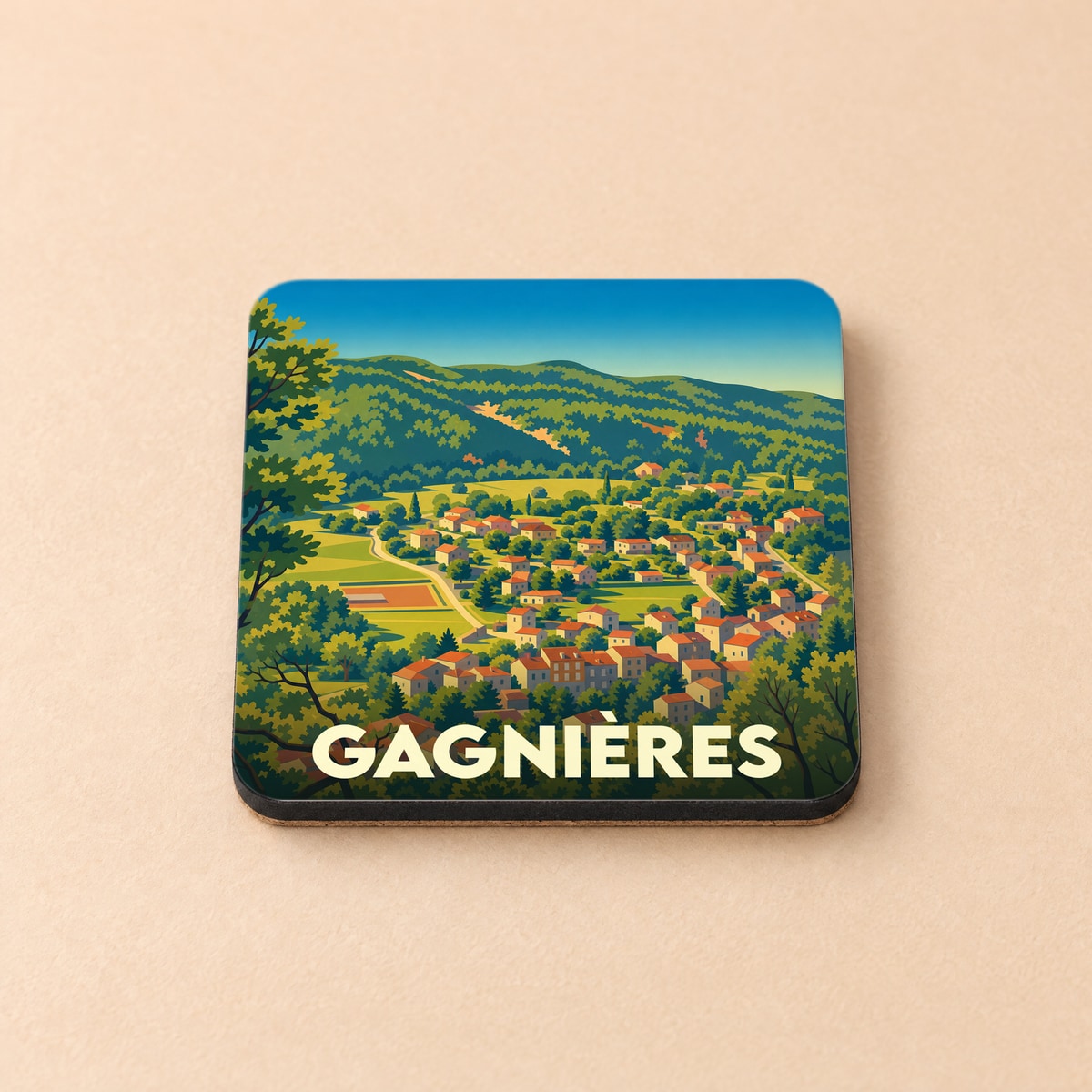 Dessous de verre souvenir de la ville de Gagnières avec une illustration stylisée d'un village dans une vallée verdoyante.