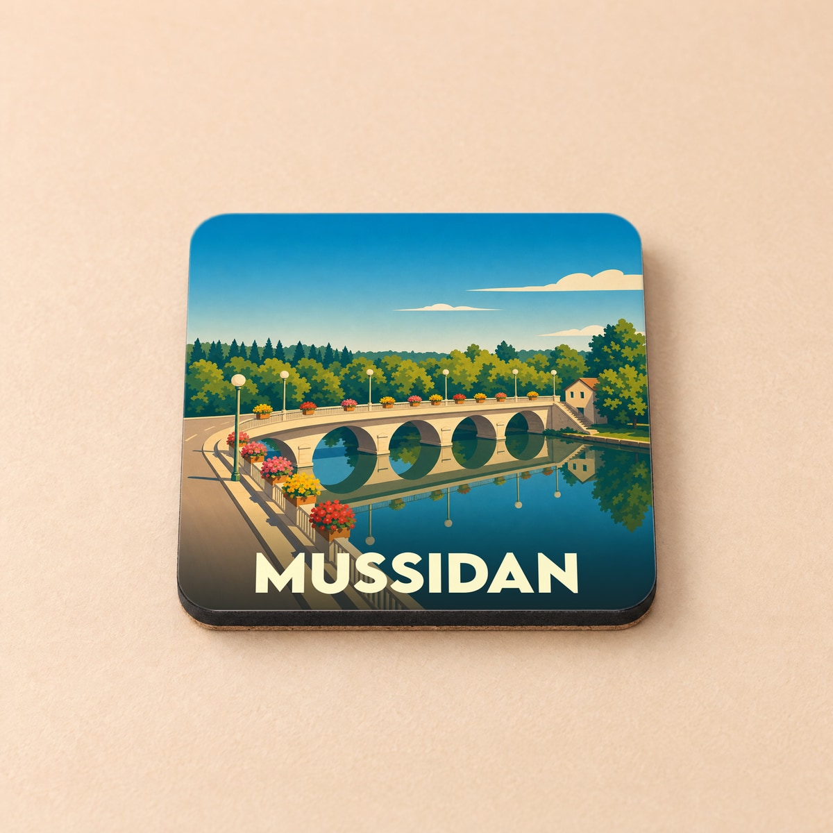 Dessous de verre souvenir de la ville de Mussidan avec une illustration stylisée de son pont fleuri.