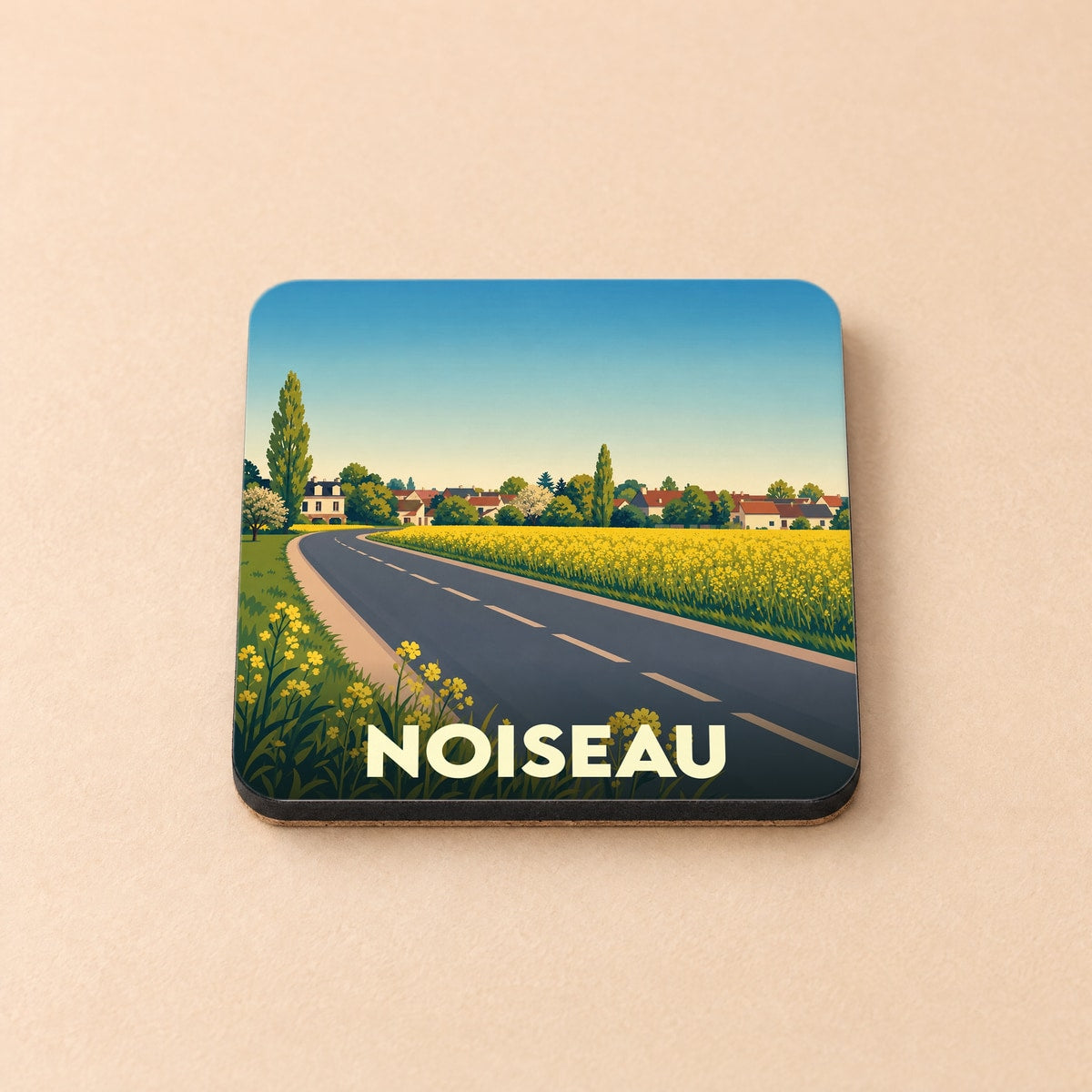 Dessous de verre souvenir de la ville de Noiseau avec une illustration stylisée de route bordée de champs.