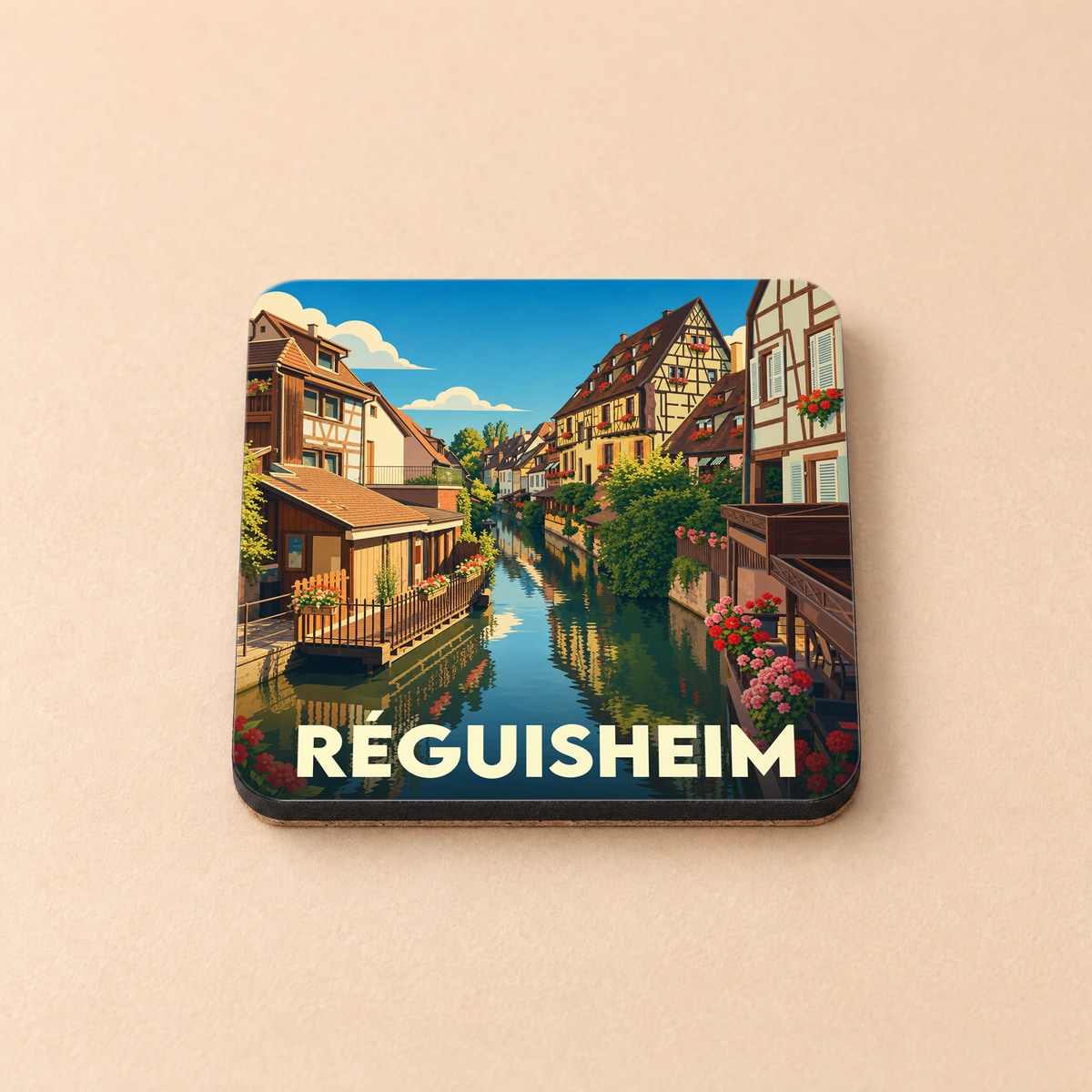 Dessous de verre souvenir de la ville de Réguisheim avec une illustration stylisée d'un canal bordé de maisons à colombages.