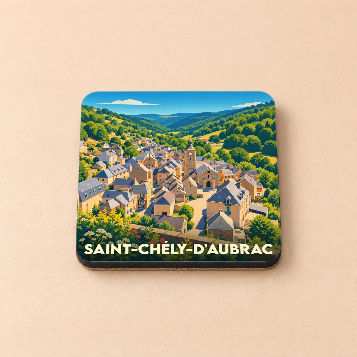 Dessous de verre souvenir de Saint-Chély-d'Aubrac avec une illustration colorée et stylisée du village dans la vallée.