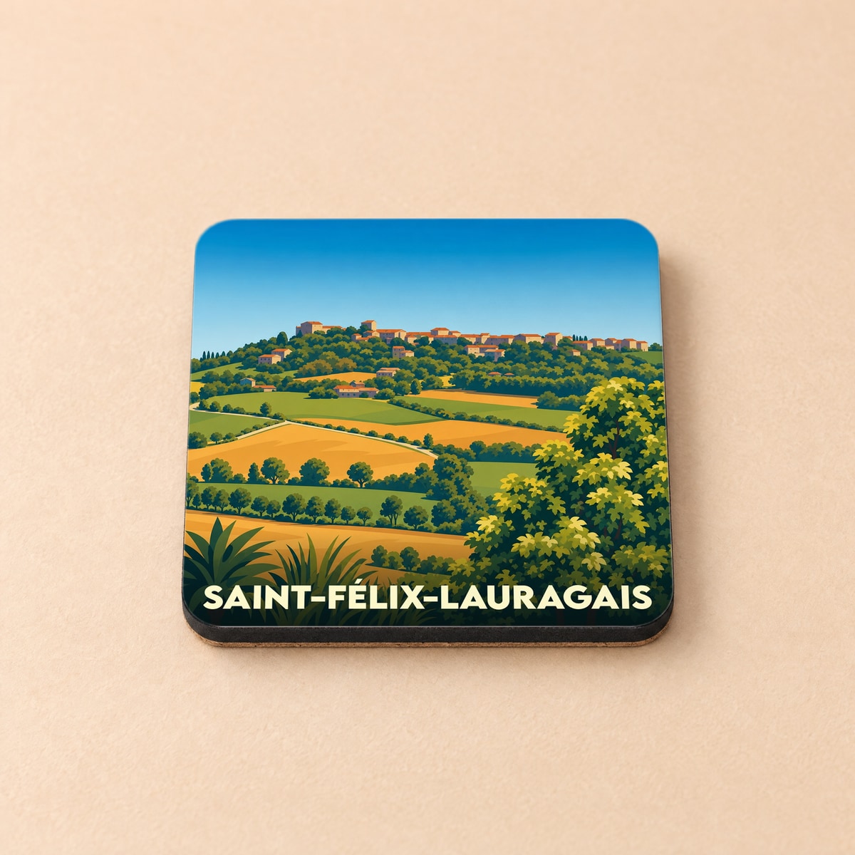 Dessous de verre souvenir de la ville de Saint-Félix-Lauragais avec une illustration stylisée de paysages vallonnés.