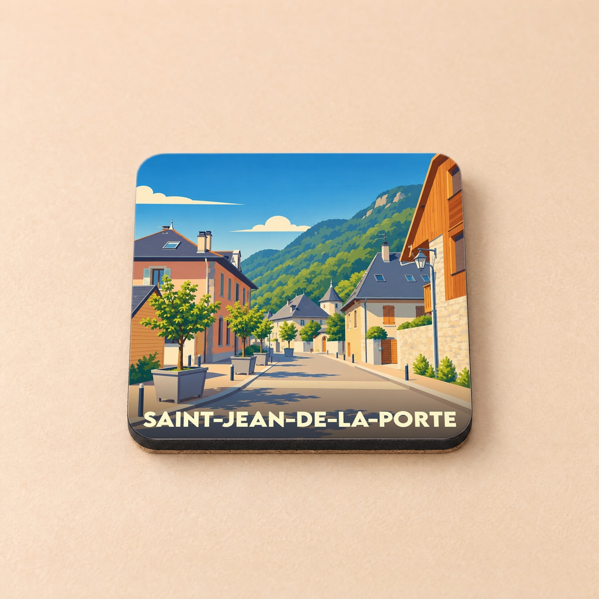Dessous de verre souvenir de la ville de Saint-Jean-de-la-Porte avec une illustration stylisée d'une rue de village en montagne.