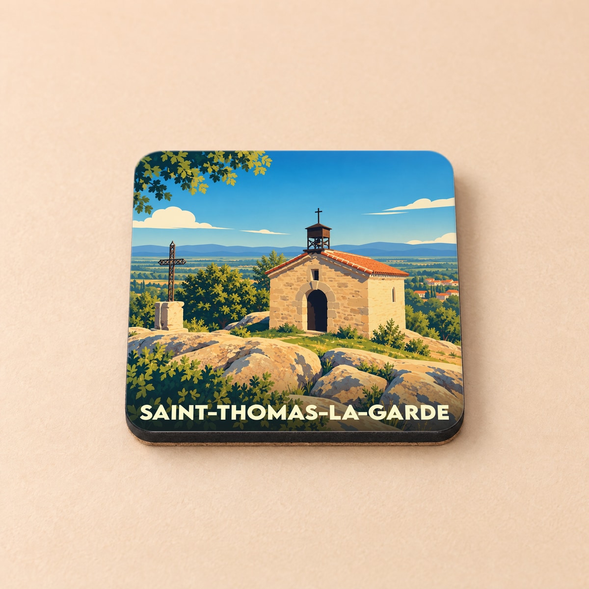 Dessous de verre souvenir de la ville de Saint-Thomas-la-Garde avec une illustration stylisée d'une chapelle en pierre.