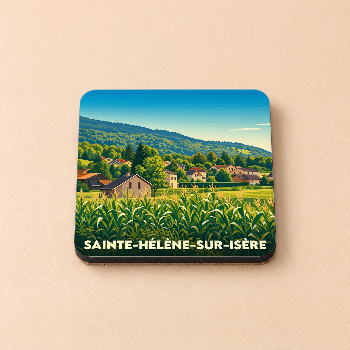 Dessous de verre souvenir de Sainte-Hélène-sur-Isère illustré d'un paysage de village alpin et de champs.