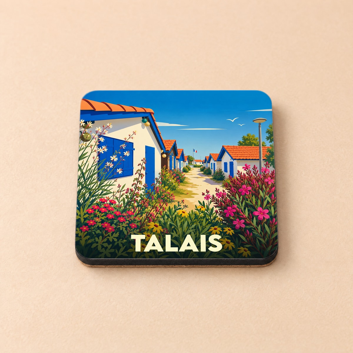 Dessous de verre souvenir de la ville de Talais avec une illustration stylisée de maisons côtières fleuries.