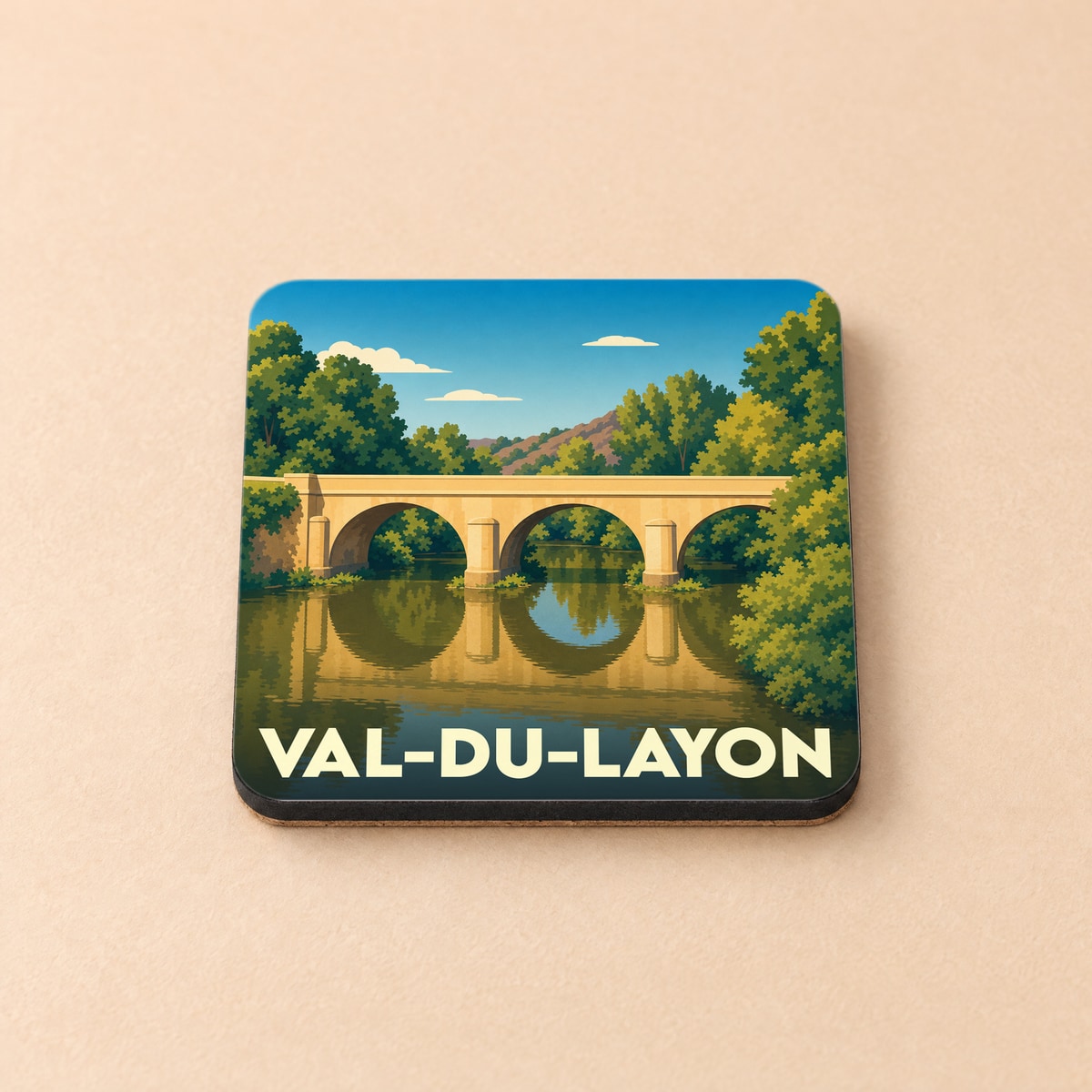 Dessous de verre souvenir de Val-du-Layon arborant une illustration stylisée d'un pont en pierre traversant une rivière bordée d'arbres.