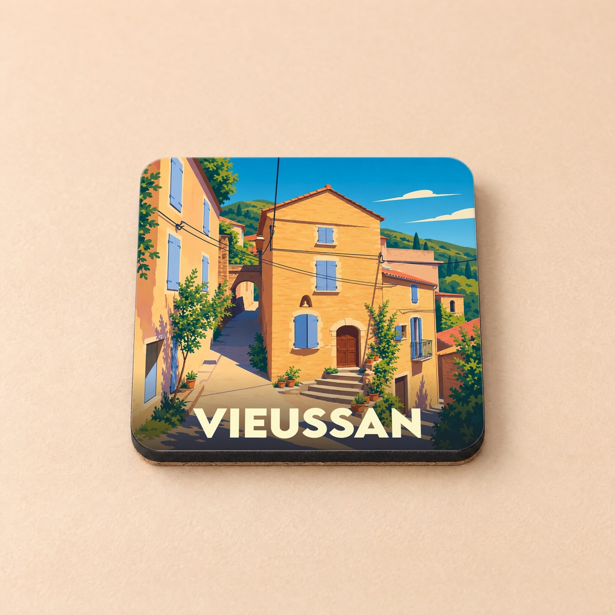 Dessous de verre souvenir de la ville de Vieussan avec une illustration stylisée d'un village occitan.