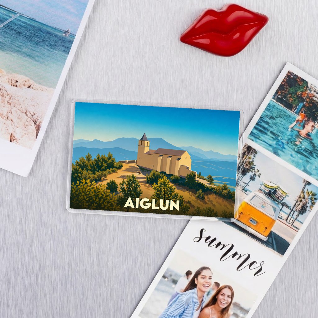 Magnet souvenir de la ville d'Aiglun illustrant une église de montagne sous un ciel bleu.
