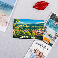 Magnet souvenir de la ville d'Arfeuilles illustrant un paysage de campagne vallonné avec une église.