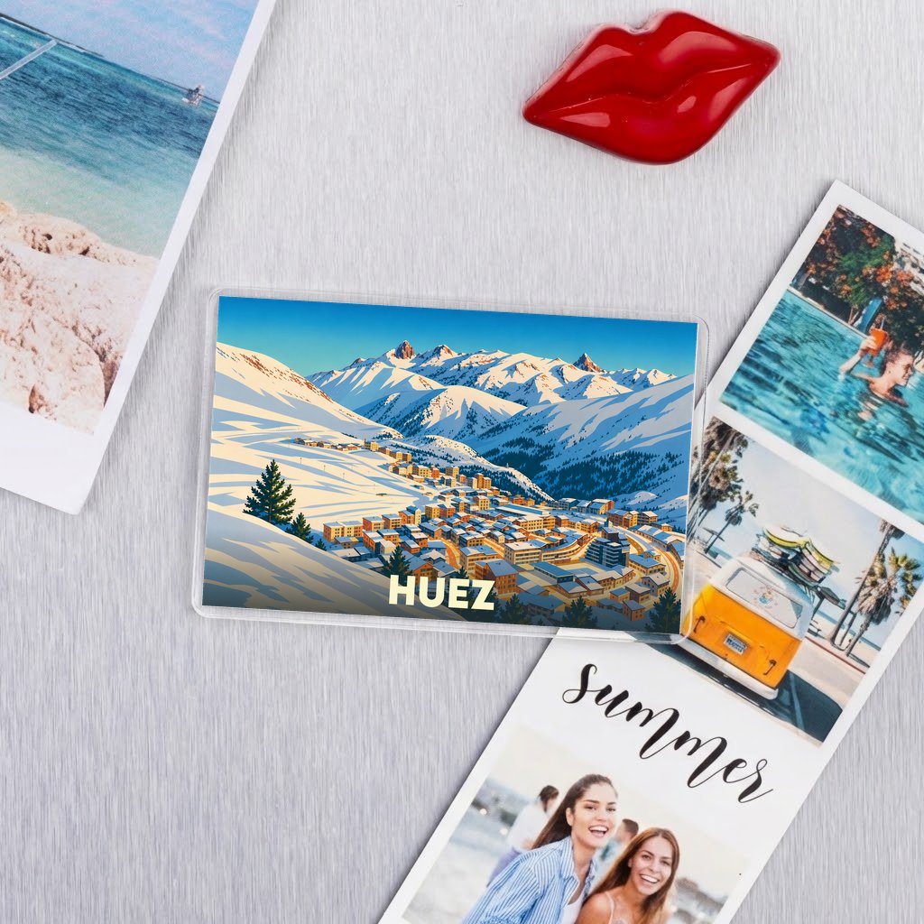 Magnet souvenir de la ville de Huez avec une illustration de paysages montagneux enneigés.