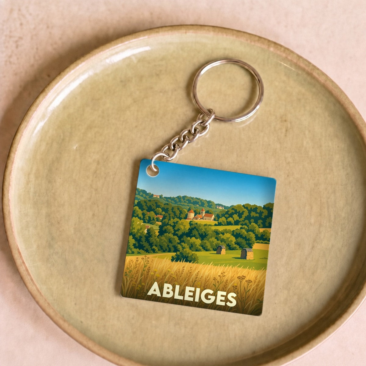 Porte-clés souvenir de la ville de Ableiges avec une illustration stylisée de son paysage champêtre.