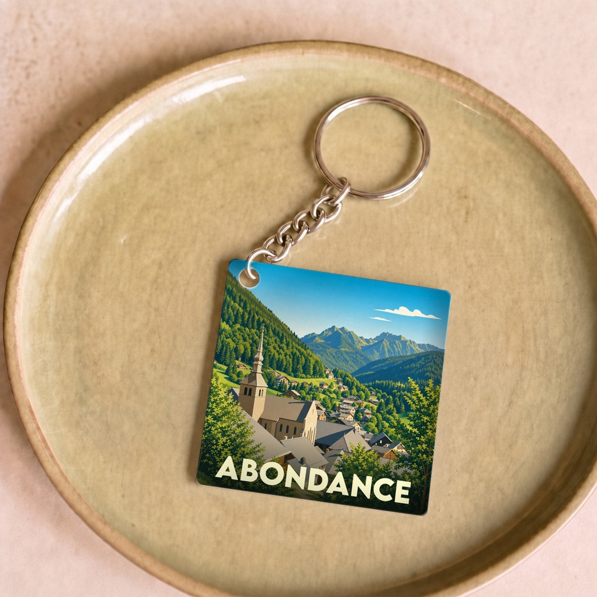 Porte-clés souvenir de la ville d'Abondance avec une illustration stylisée de son église et des montagnes.
