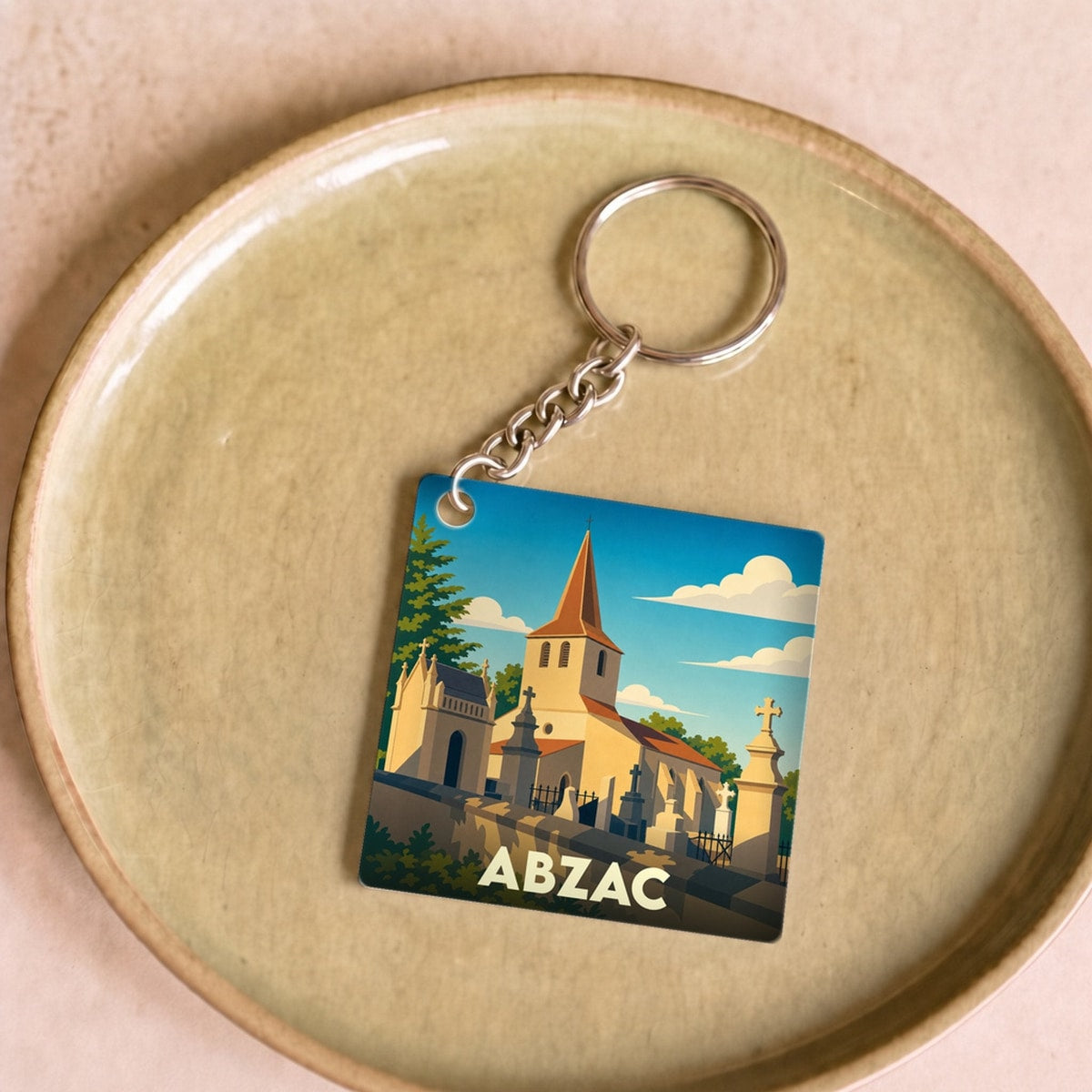 Porte-clés souvenir de la ville d'Abzac avec une illustration stylisée de son église.