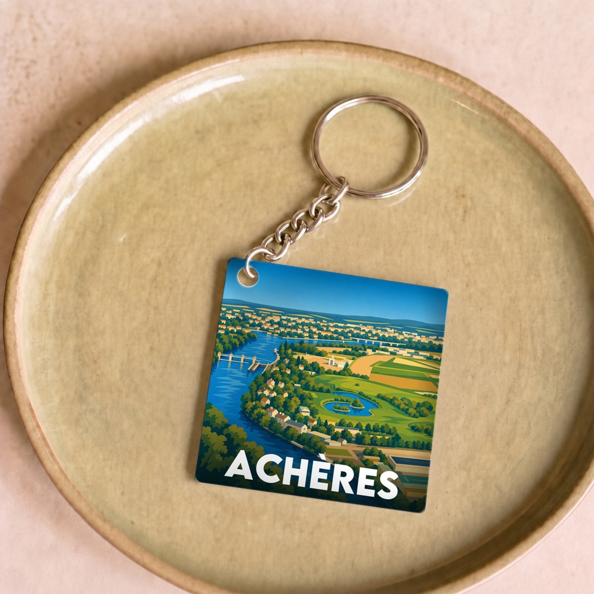 Porte-clés souvenir de la ville d'Achères avec une illustration stylisée de son paysage.