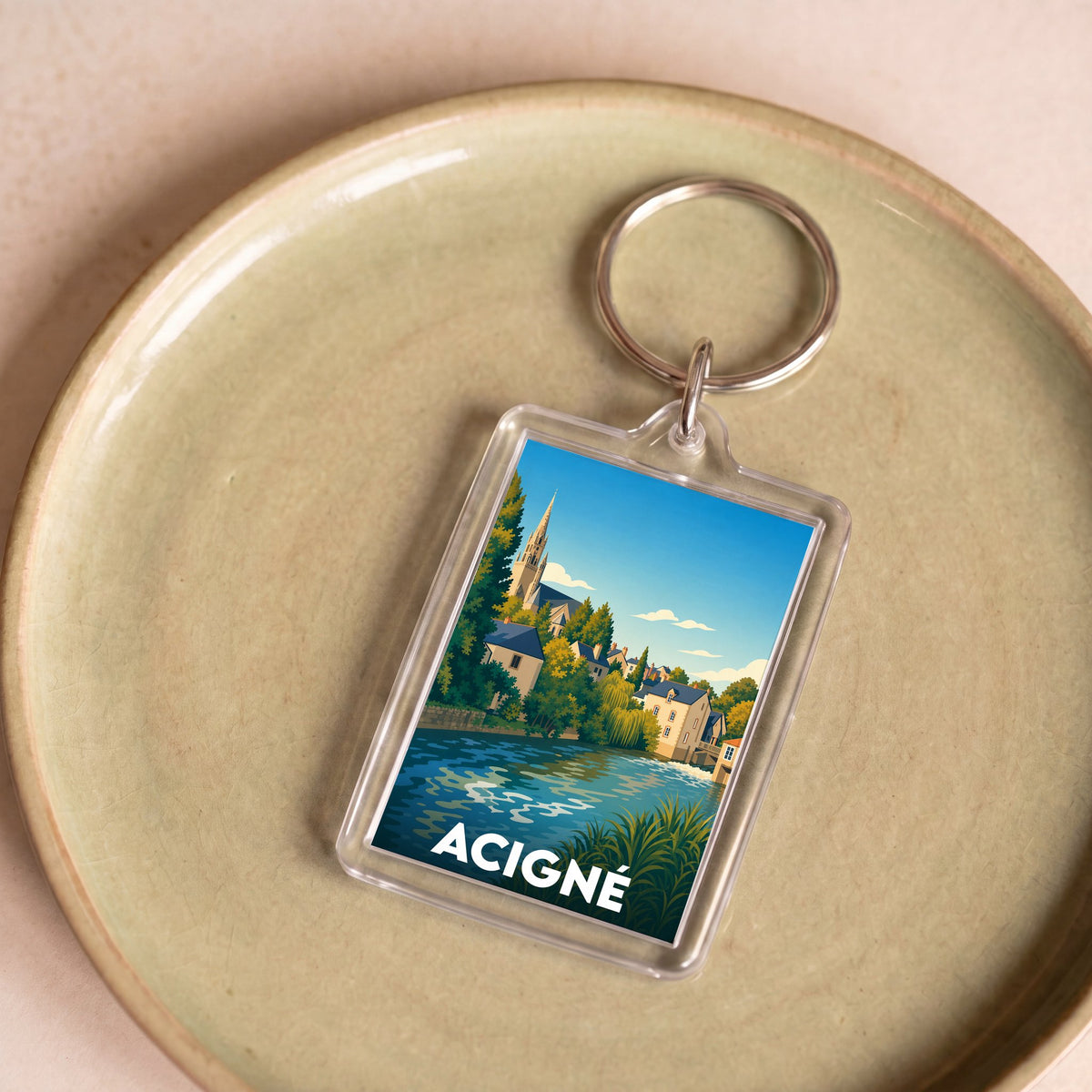 Porte-clés souvenir de la ville d'Acigné avec une illustration stylisée et colorée.