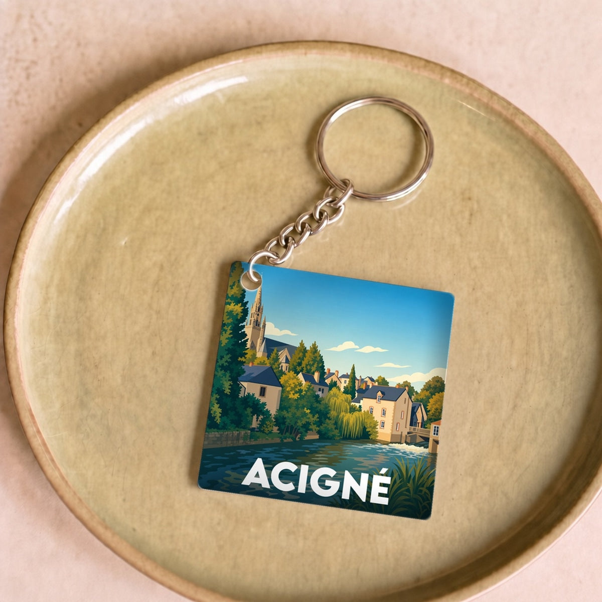 Porte-clés souvenir de la ville d'Acigné avec une illustration stylisée et colorée.