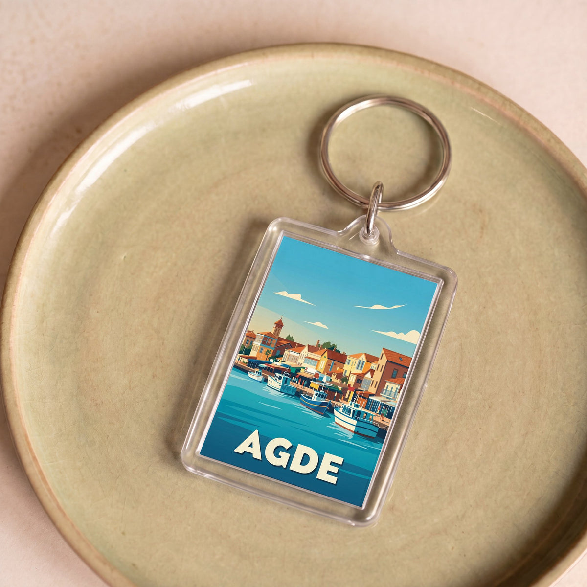 Porte-clés souvenir de la ville d'Agde avec une illustration stylisée du port.