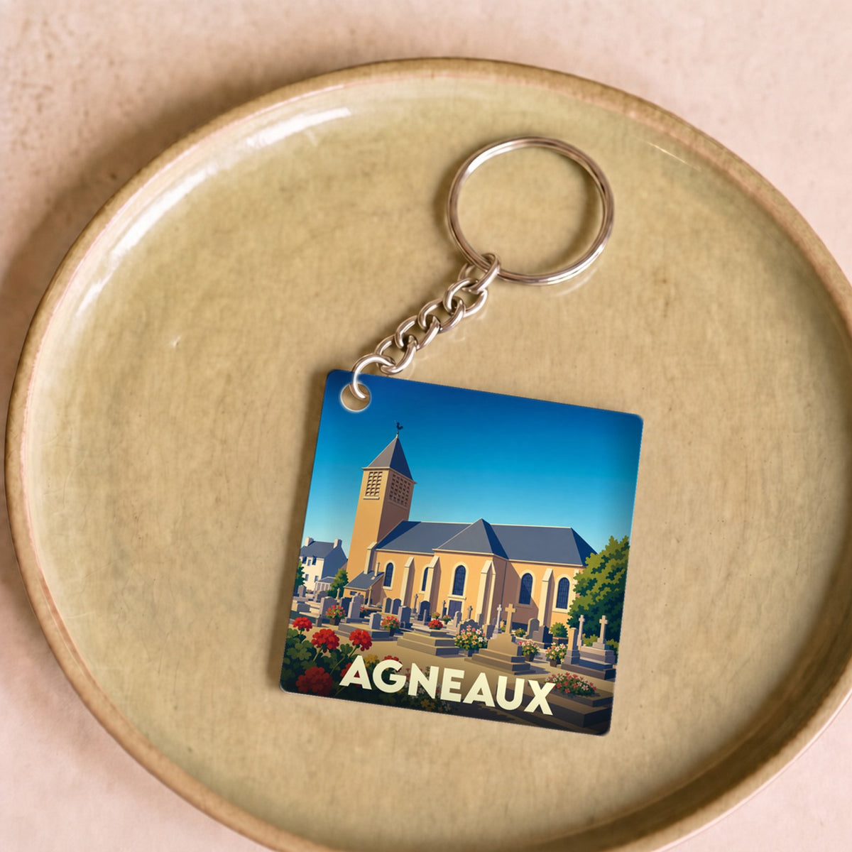 Porte-clés souvenir de la ville d'Agneaux avec une illustration stylisée de son église.