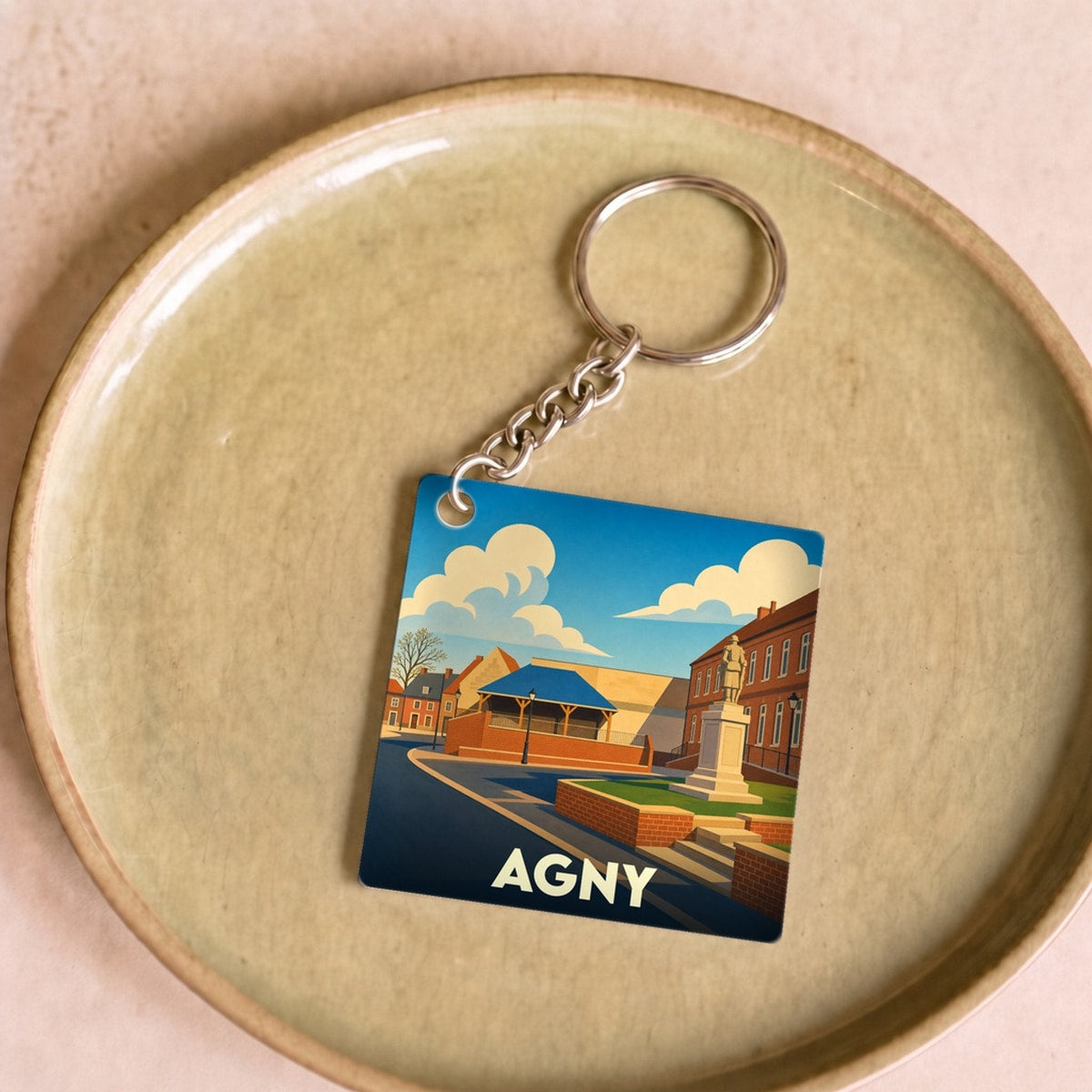 Porte-clés souvenir de la ville d'Agny avec une illustration stylisée.
