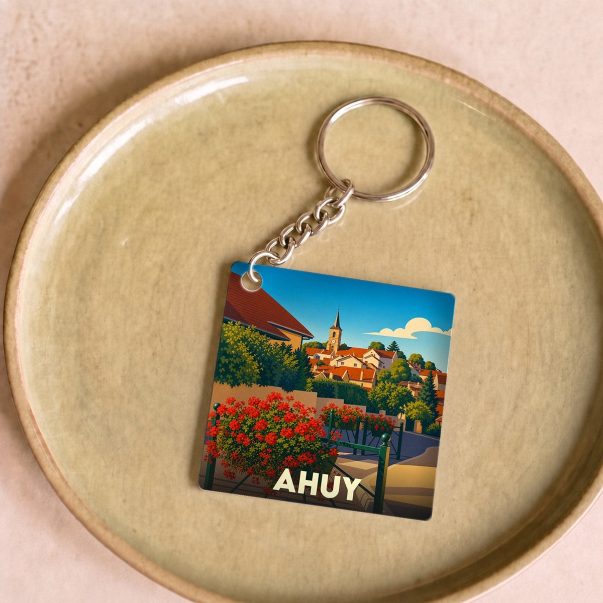 Porte-clés souvenir de la ville d'Ahuy avec une illustration stylisée et colorée.