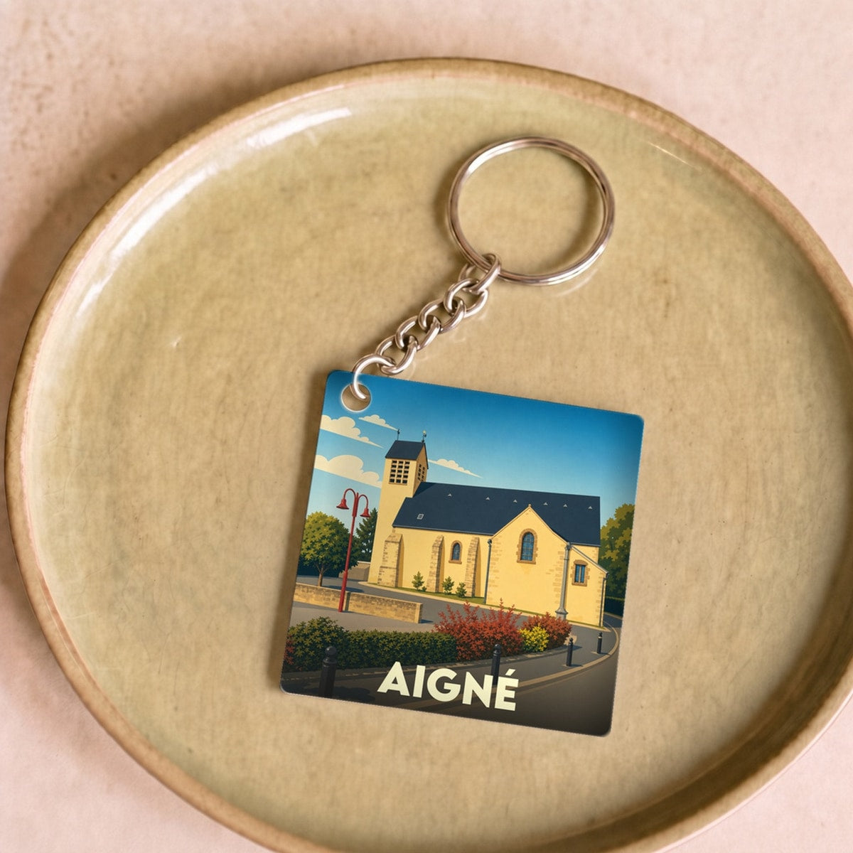 Porte-clés souvenir de la ville d'Aigné avec une illustration stylisée de son église.