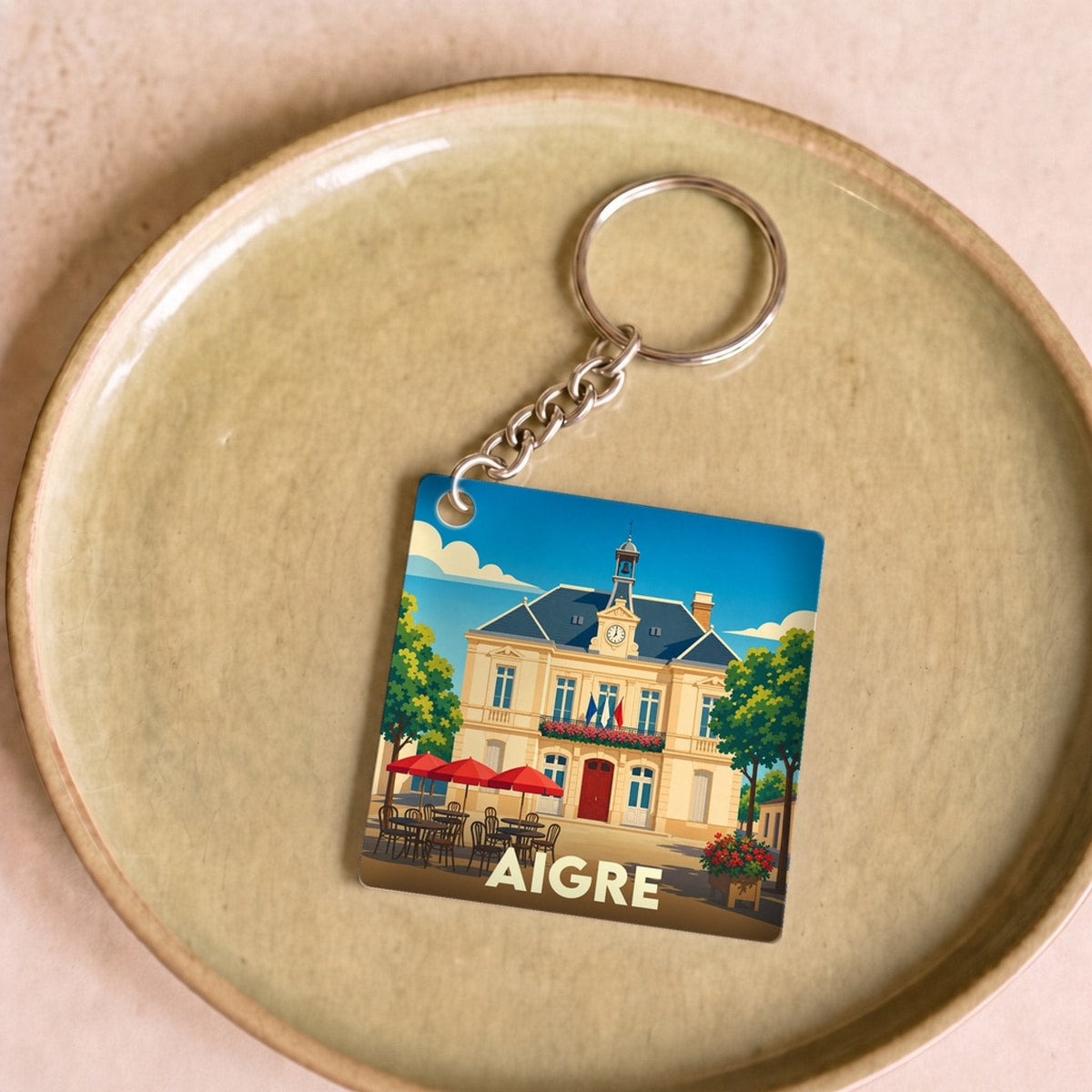 Porte-clés souvenir de la ville d'Aigre avec une illustration stylisée de sa mairie.