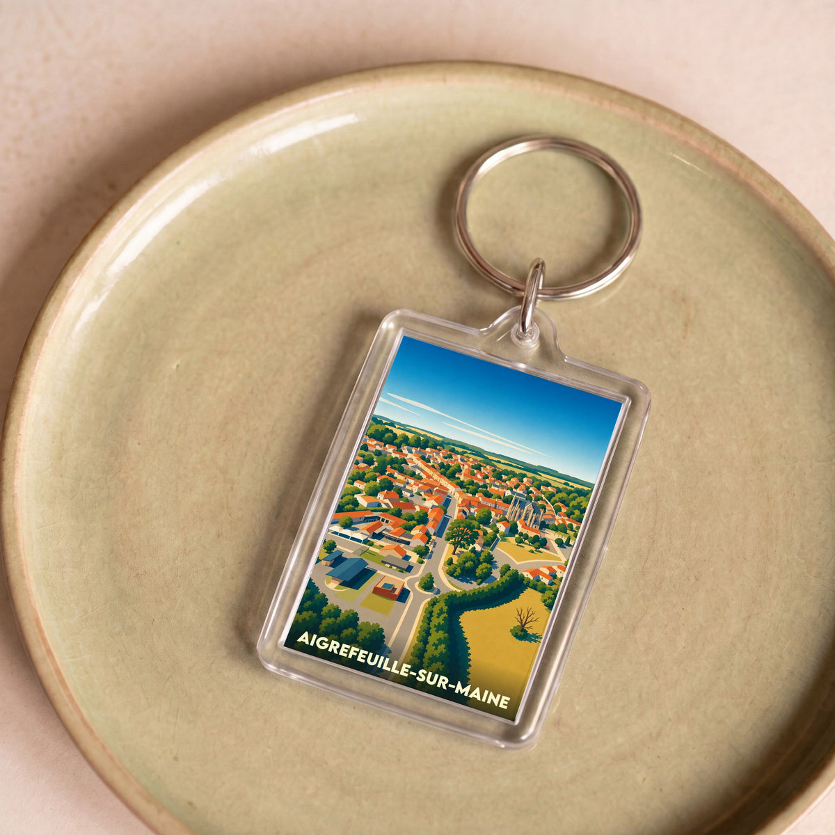 Porte-clés souvenir de la ville de Aigrefeuille-sur-Maine avec une illustration stylisée vue du ciel.