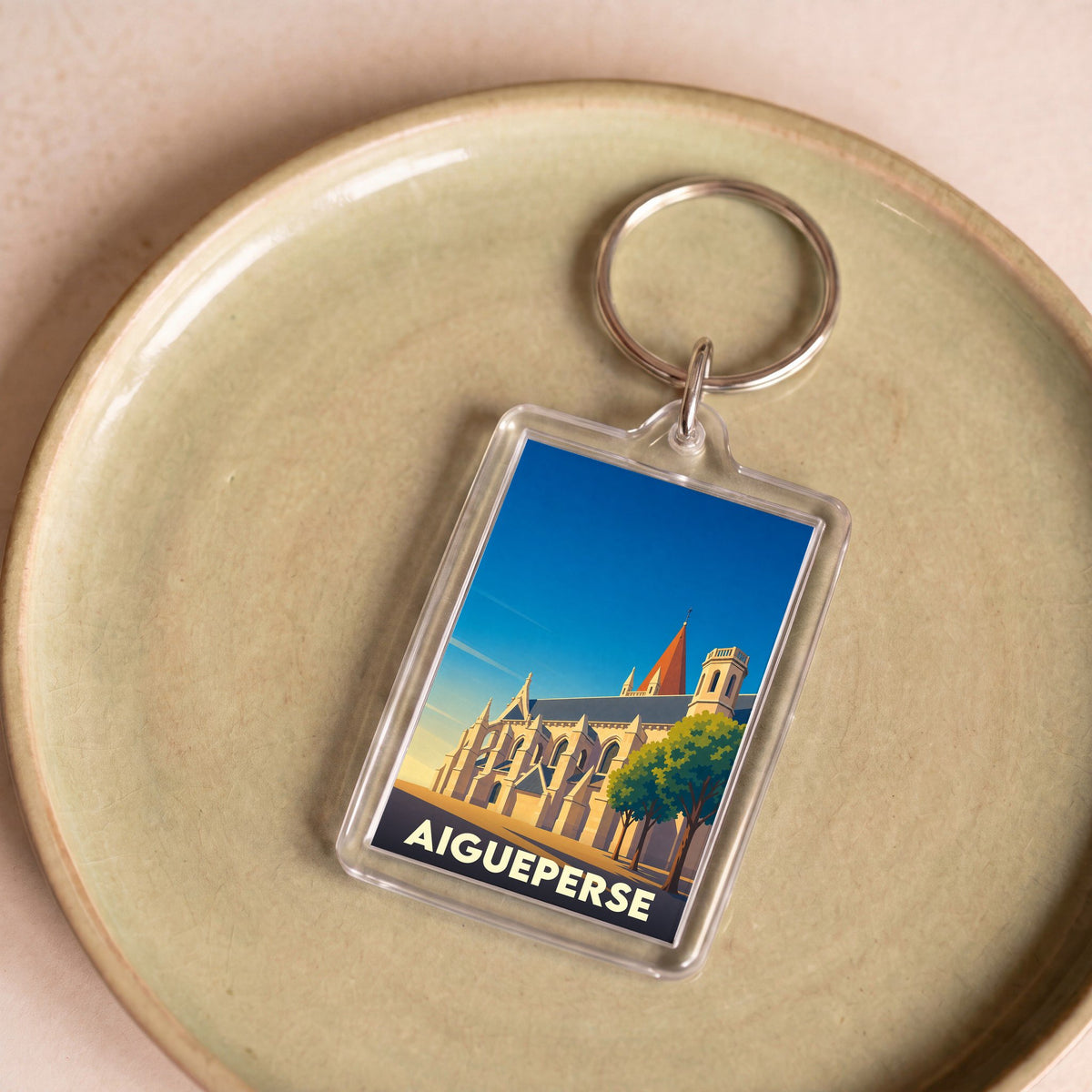 Porte-clés souvenir de la ville d'Aigueperse avec une illustration stylisée de son église.