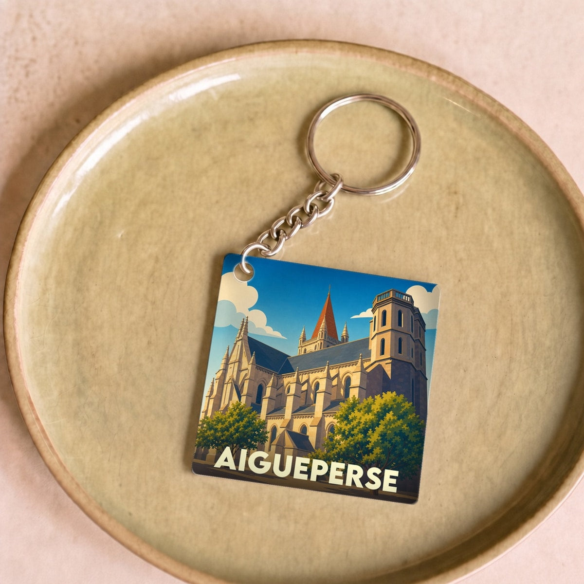 Porte-clés souvenir de la ville d'Aigueperse avec une illustration stylisée de son église.
