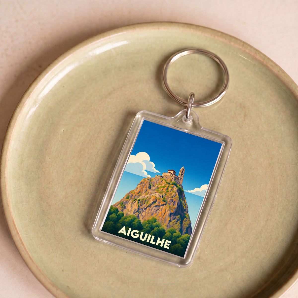 Porte-clés souvenir de la ville d'Aiguilhe avec une illustration stylisée de son rocher et de sa chapelle.