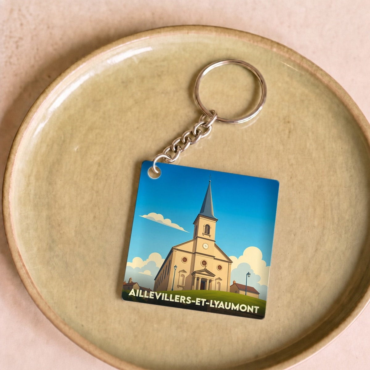 Porte-clés souvenir de la ville d'Aillevillers-et-Lyaumont avec une illustration stylisée de son église.
