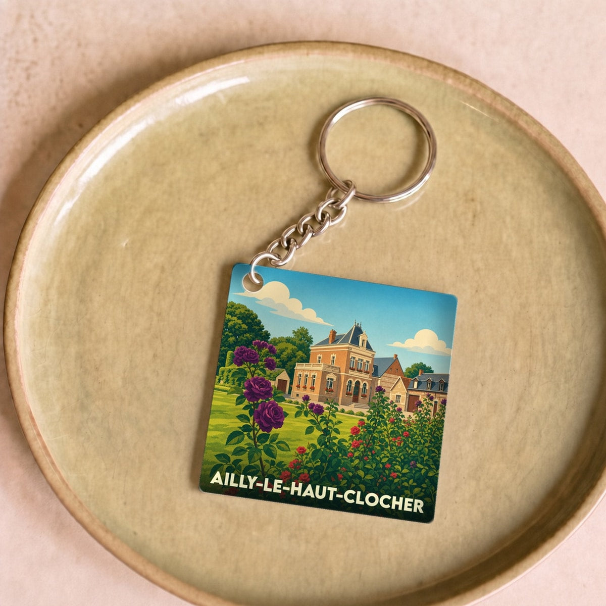 Porte-clés souvenir de la ville de Ailly-le-Haut-Clocher avec une illustration colorée et fleurie.