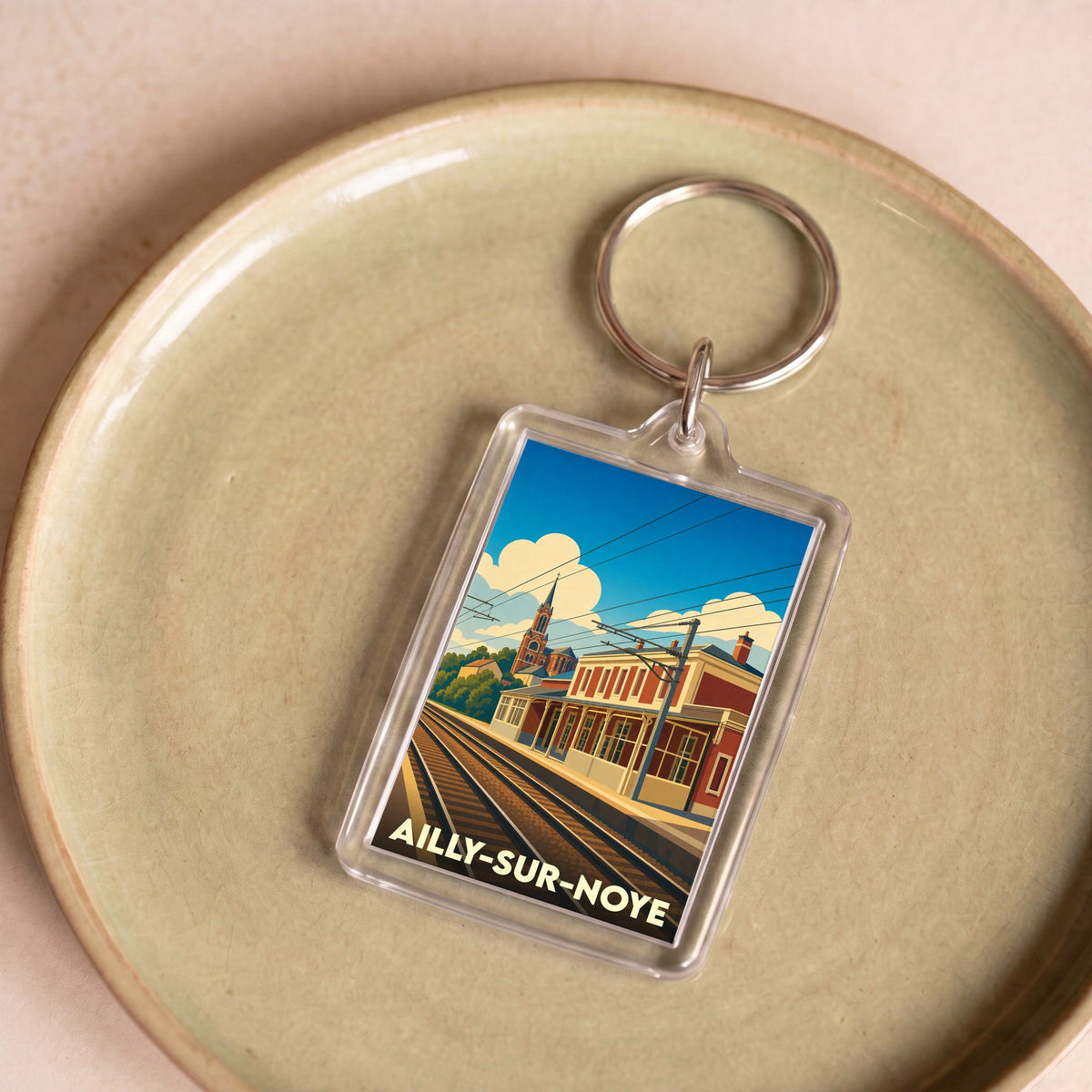 Porte-clés souvenir de la ville de Ailly-sur-Noye avec une illustration stylisée de sa gare.
