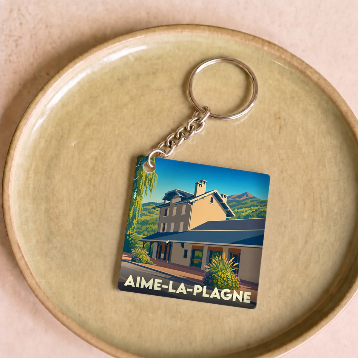Porte-clés souvenir de la ville de Aime-la-Plagne avec une illustration stylisée.