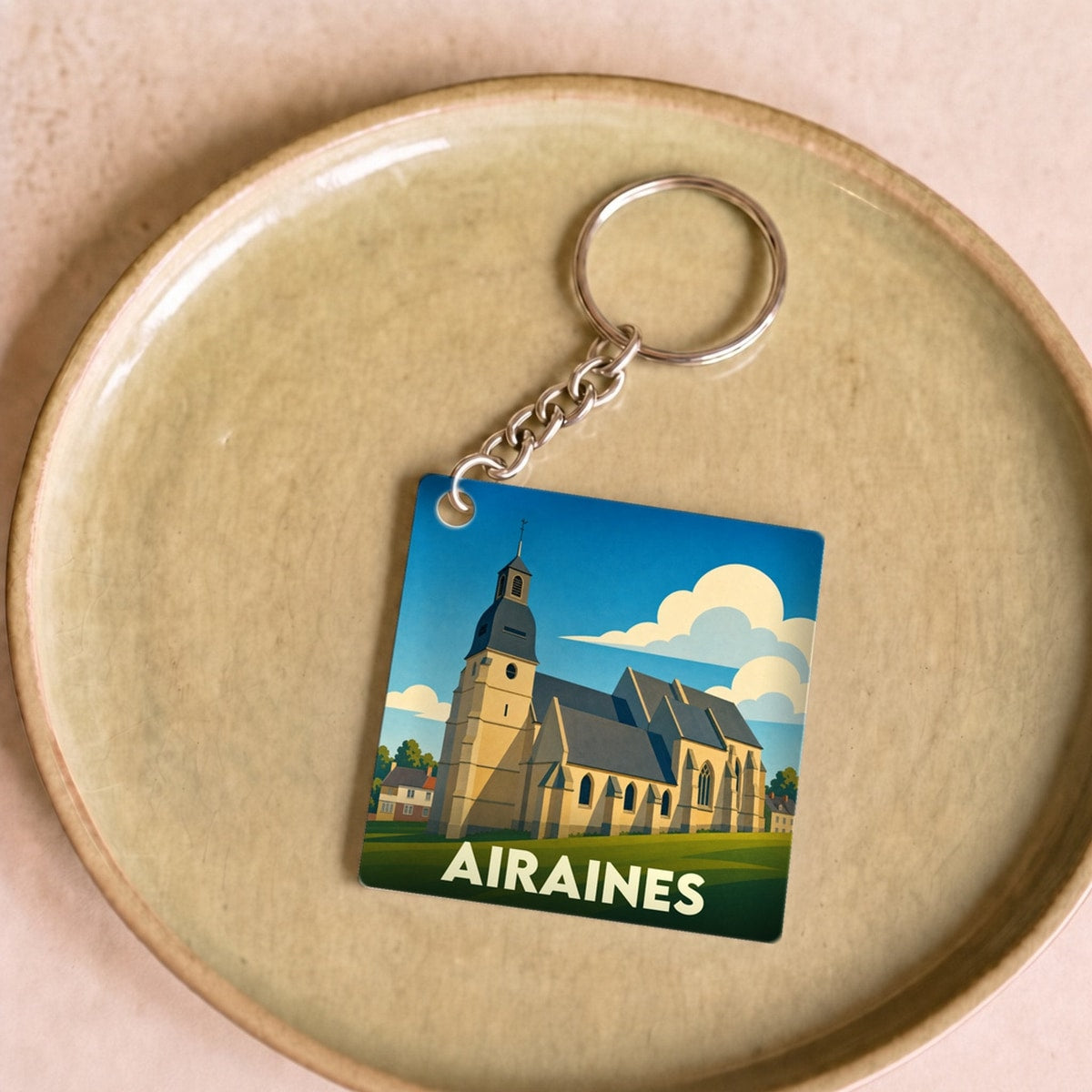 Porte-clés souvenir de la ville d'Airaines avec une illustration stylisée de son église.