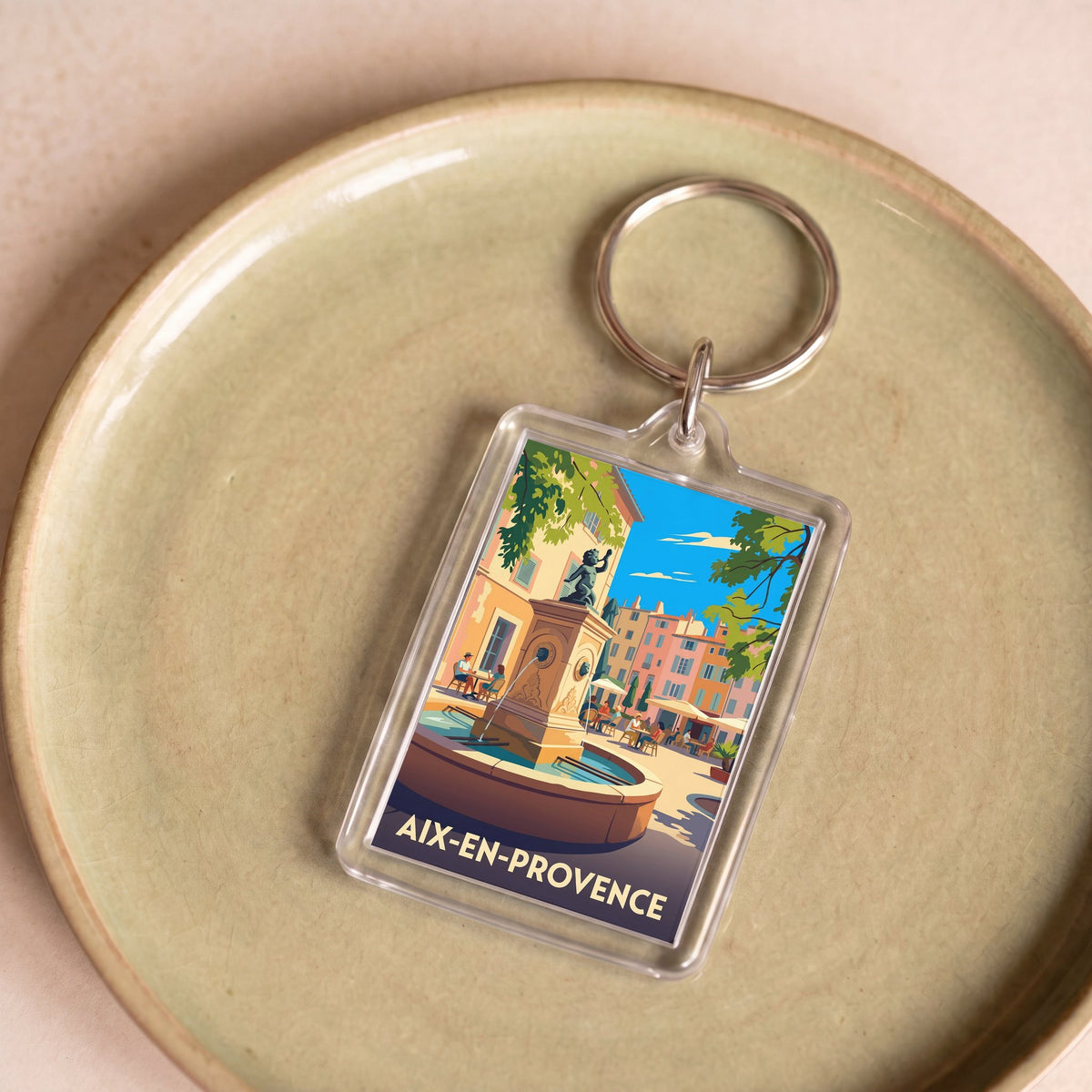 Porte-clés souvenir de la ville d'Aix-en-Provence avec une illustration stylisée d'une place ensoleillée.