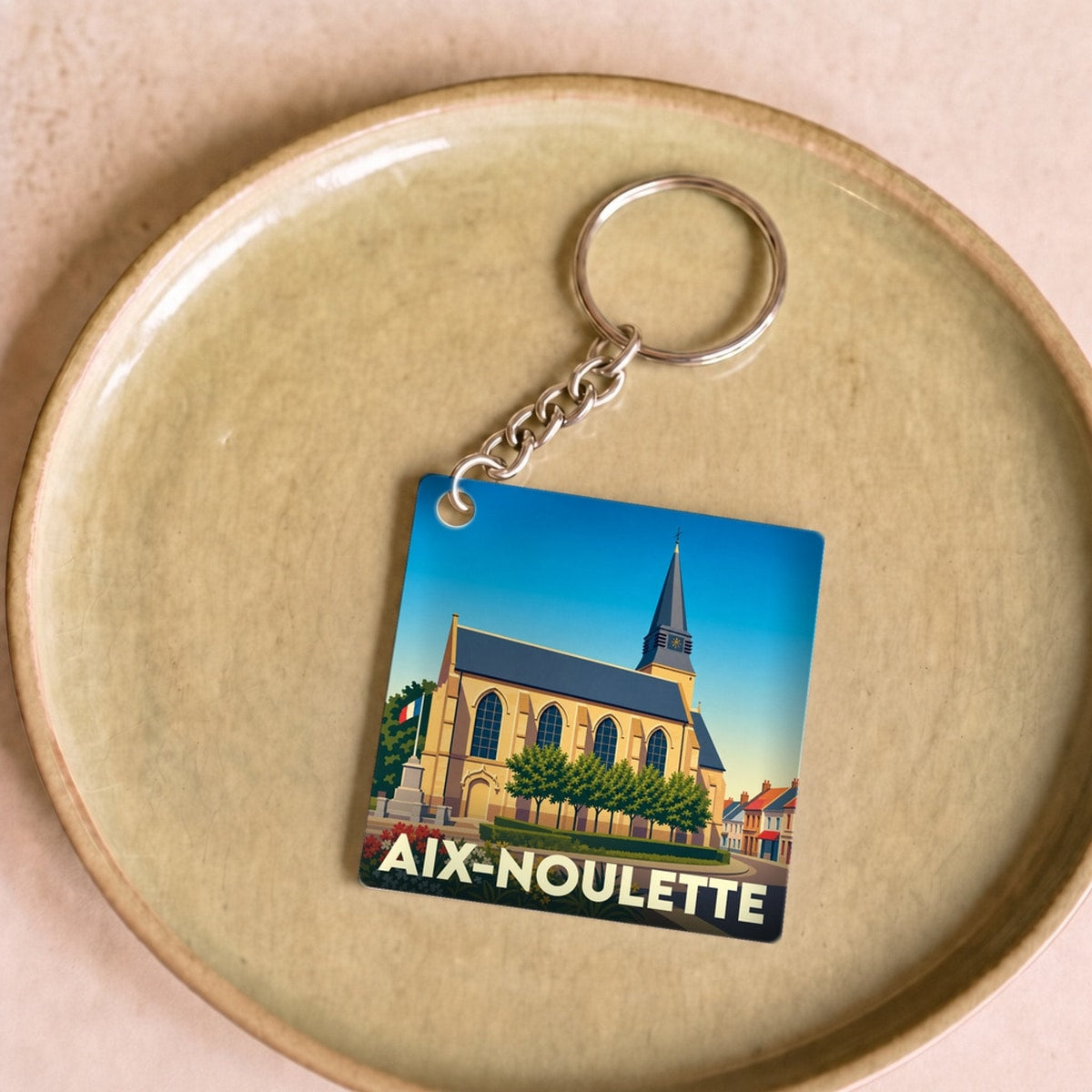 Porte-clés souvenir de la ville d'Aix-Noulette avec une illustration stylisée de son église.