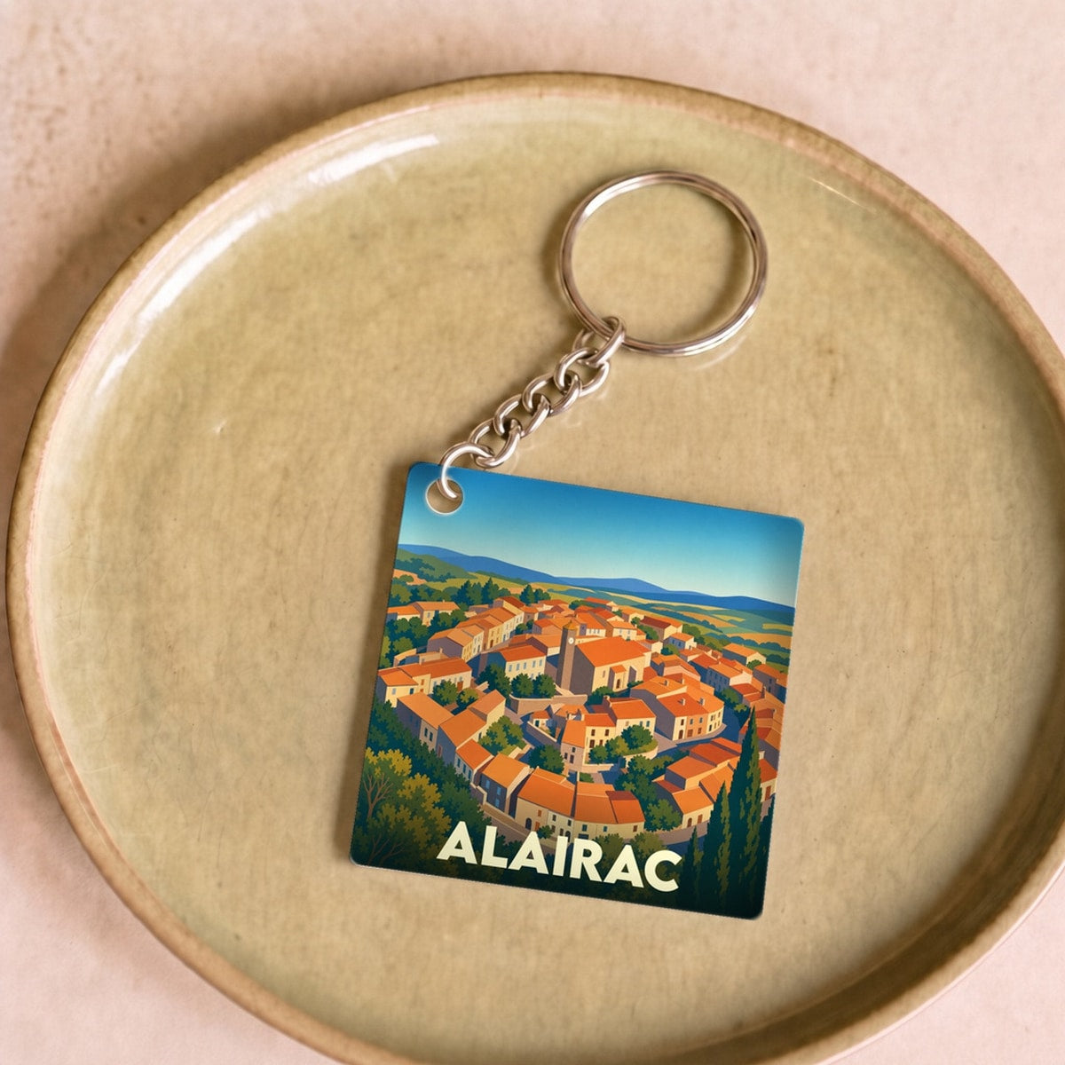 Porte-clés souvenir de la ville d'Alairac avec une illustration stylisée.