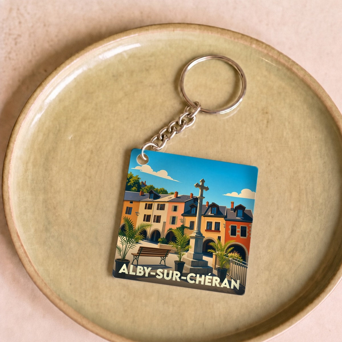 Porte-clés souvenir de la ville d'Alby-sur-Chéran avec une illustration stylisée de sa place centrale.